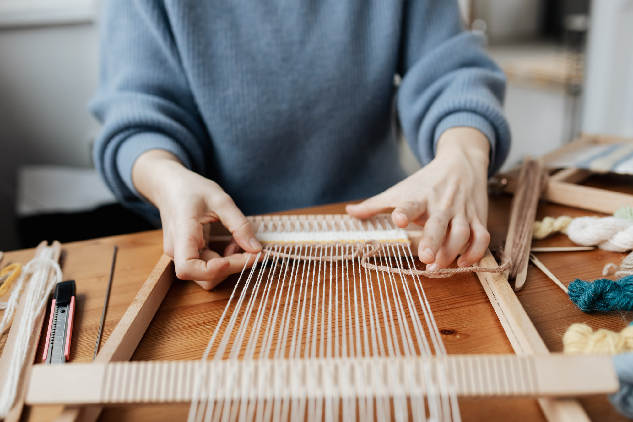 Hands weaving on a loom